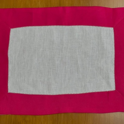 Toalhete cinza claro com borda cor-de-rosa sobre madeira clara