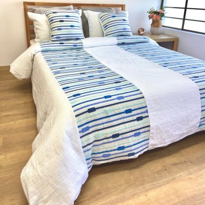 Cama com roupa de cama azul e branca com padrão riscado