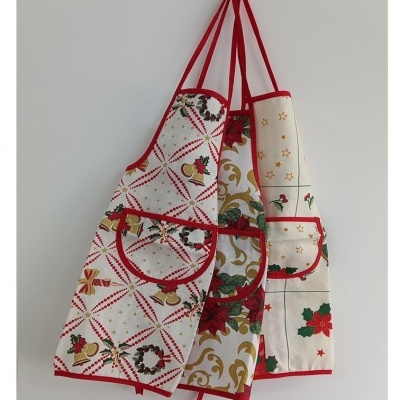 Três aventais de cozinha com padrões natalícios pendurados numa parede branca.