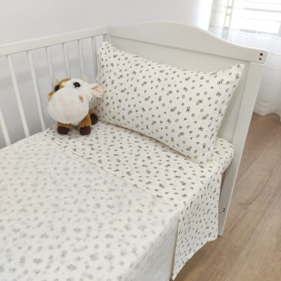 Cama infantil branca com roupa de cama floral e peluche de vaca
