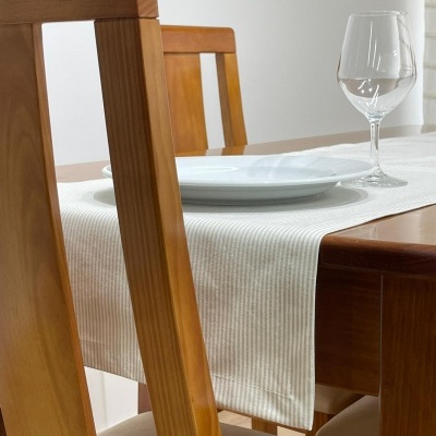 cadeiras e mesa de jantar em madeira clara com toalha branca e louça