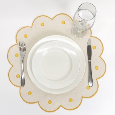 Conjunto de jantar com guardanapo branco e amarelo, pratos brancos, talheres metálicos e copo de vidro