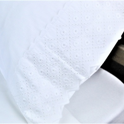 Tecido branco bordado com padrão floral e bordas onduladas