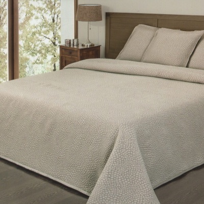 Conjunto de cama bege com padrão geométrico em quarto com luz natural