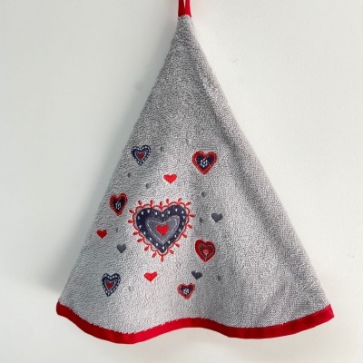 Toalha cinzenta com corações bordados e bainha vermelha pendurada na parede