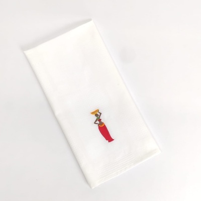 Guardanapo branco com bordado de figura feminina a carregar cesto.