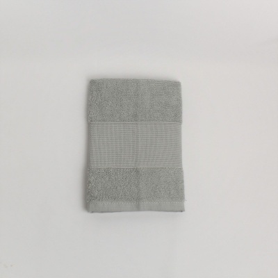 Toalha cinzenta dobrada com faixa no centro sobre fundo branco.