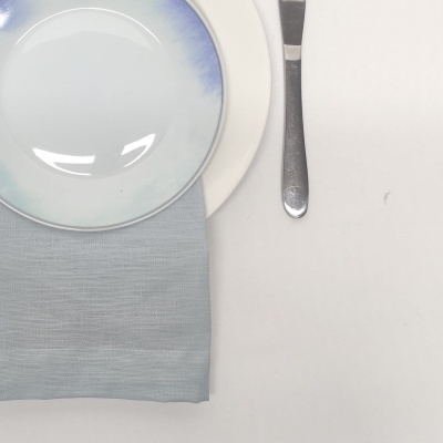 Conjunto de pratos e talher sobre toalha cinzenta e fundo branco