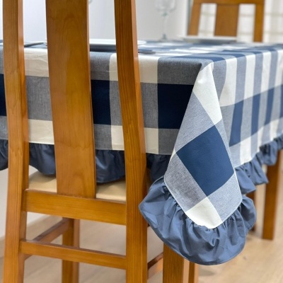 Toalha de mesa xadrez azul e branco com bordas franzidas em mesa de madeira e cadeiras de madeira