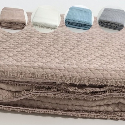 Colcha acolchoada castanho claro com quatro amostras de cor sobre fundo branco