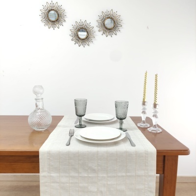 Mesa de madeira com louças e copos sobre toalha branca e espelhos decorativos na parede