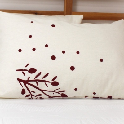 Travesseiro branco com desenho de ramos e bolinhas vinho