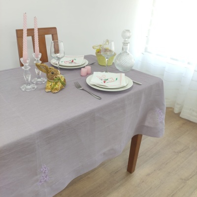 Mesa arrumada com toalha cinzenta e decoração de coelho de cerâmica e castiçais com velas rosa