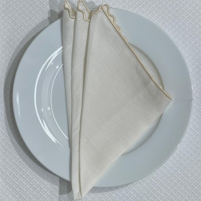 Guardanapos brancos com borda dourada sobre um prato branco redondo