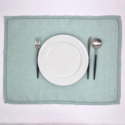 Conjunto de prato branco com talheres de cabo preto sobre individual verde claro