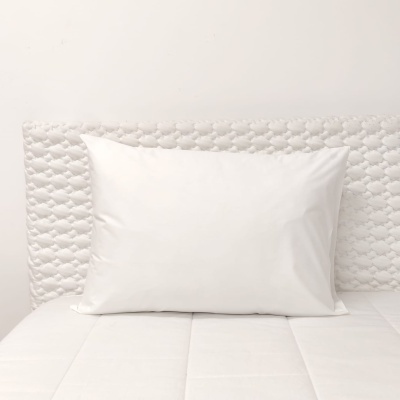 Almofada branca numa cama com cabeceira acolchoada