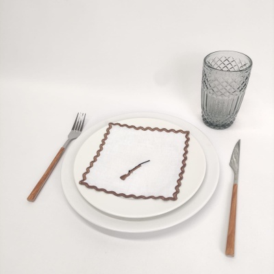 Conjunto de pratos, talheres de madeira, guardanapo com borda castanha e copo de vidro transparente