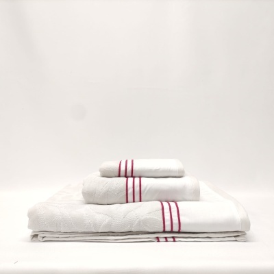 Conjunto de toalhas brancas com riscas vermelhas empilhadas sobre superfície branca