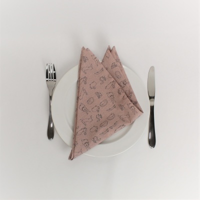 Guardanapo rosa com padrão preto num prato branco com talheres ao lado