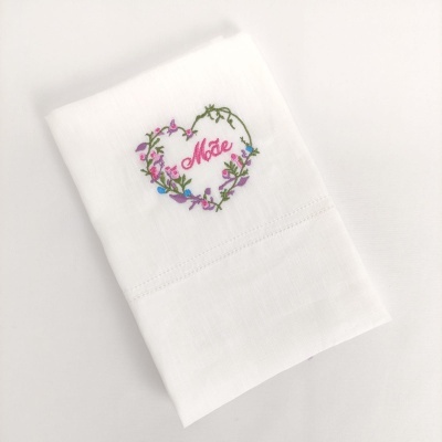 Toalha branca de linho com bordado colorido em forma de coração com a palavra Mãe