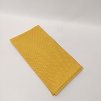Toalha amarela dobrada com textura quadriculada sobre fundo branco