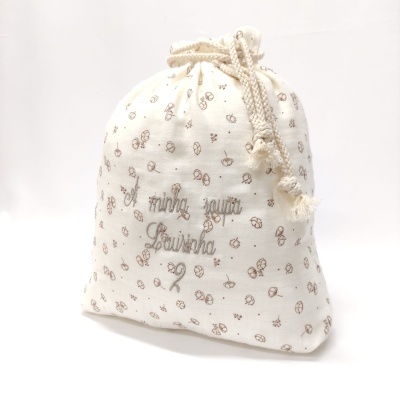 Saco de tecido cru com padrão de flores e cordão de algodão com texto bordado.