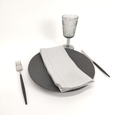 Conjunto de refeição cinza com guardanapo branco, talheres pretos e copo de vidro decorado
