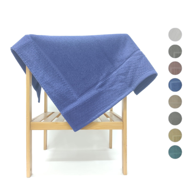 Manta azul com textura tricotada sobre estrutura de madeira clara.
