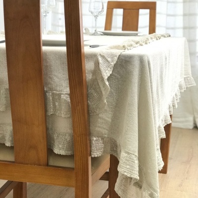 Mesa de madeira com toalha bege e cadeiras de madeira clara