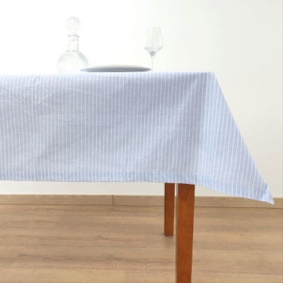 Toalha de mesa azul com riscas brancas numa mesa de madeira com prato, garrafa e taça de vidro