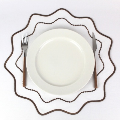 Plato branco com talheres de cabo de madeira sobre superfície branca com linha ondulada castanha