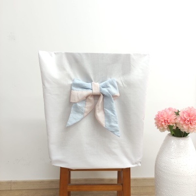Capa branca para cadeira com laço azul claro e bege, cadeira de madeira, vaso branco com flores cor de rosa