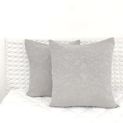 Duas almofadas cinzentas texturizadas sobre cama branca acolchoada