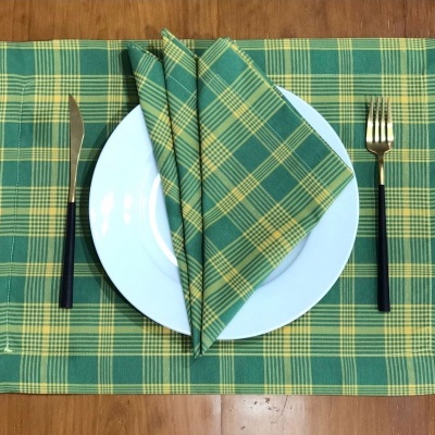 Jogo americano xadrez verde e amarelo com prato branco, guardanapo, faca e garfo