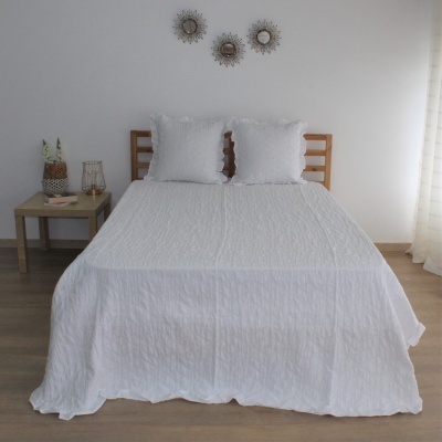 Cama de madeira com colcha e almofadas brancas em quarto minimalista