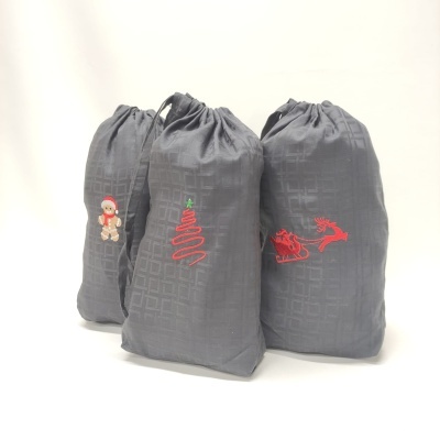 Três sacos cinza escuro com bordados natalícios e cordão de fecho