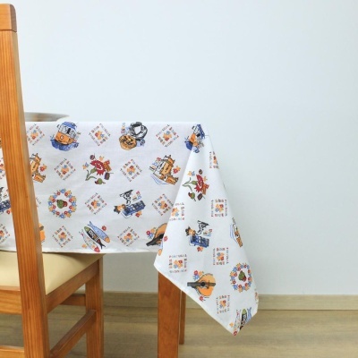Toalha de mesa estampada branca sobre mesa de madeira com cadeira ao lado