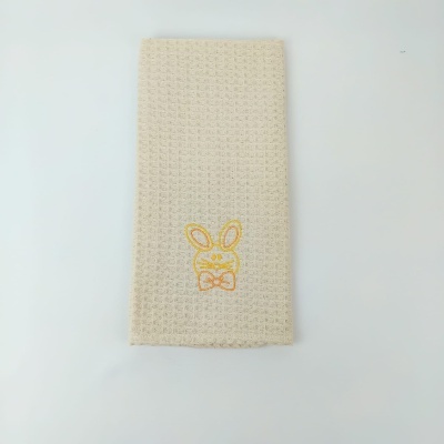 Toalha bege com bordado de coelho amarelo e laranja