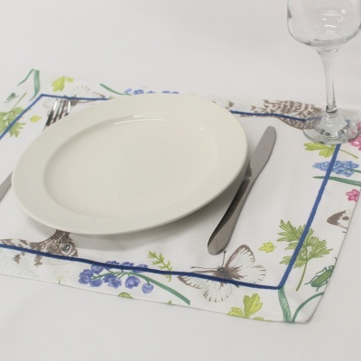 Prato branco redondo com faca e vidro sobre individual florido