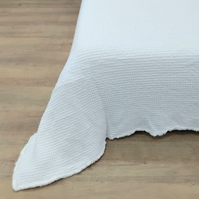 Cobertura de cama branca com textura de malha tipo waffle sobre madeira clara