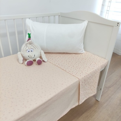 Berço branco com lençol bege e peluche de alho sorridente
