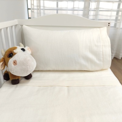 Berço com roupa de cama branca e peluche de vaca