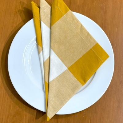 Guardanapos em tecido amarelo, bege e branco sobre prato branco