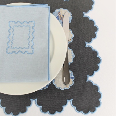 Prato branco com guardanapo azul claro bordado, faca e individual preto bordado