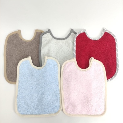 Cinco babetes de bebé coloridos em tecido felpudo sobre fundo branco