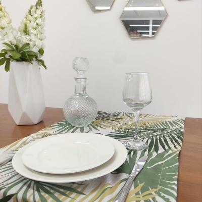 Conjunto de pratos e copo em mesa com toalha estampada e vaso com flores