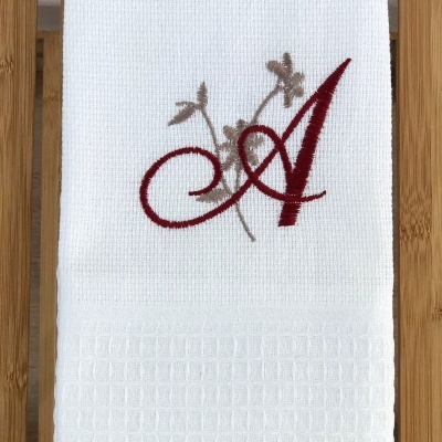 Toalha branca com bordado da letra A e flores cinzentas