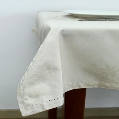 Toalha de mesa branca com padrão floral em relevo sobre mesa de madeira