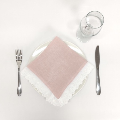 Conjunto de mesa com prato branco, guardanapos cor-de-rosa e branco, talheres prateados e copo de vidro