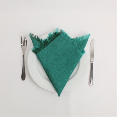 Prato branco com guardanapo verde tecido e talheres